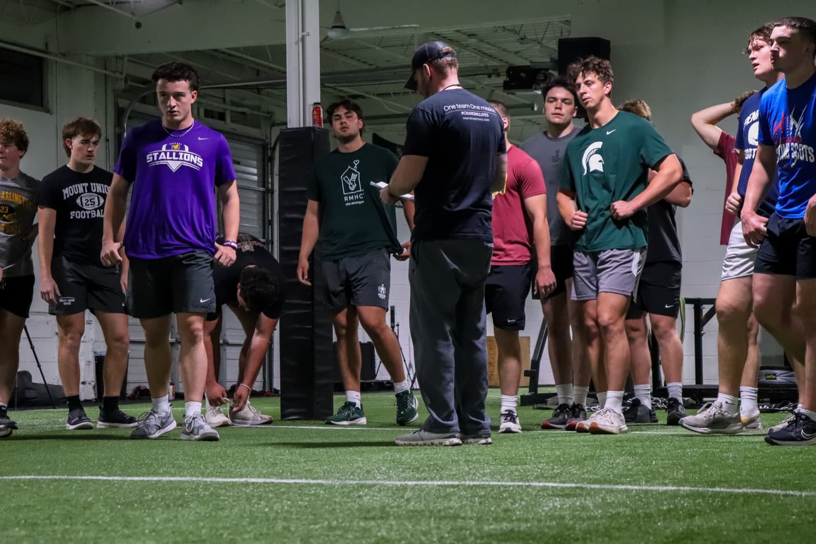 Coach Jay Hooten leading a strength and conditioning session with athletes on the turf at THE ARMORY